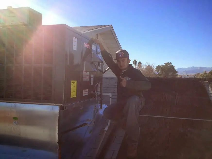 HVAC technician performing AC Tune-Up on a rooftop unit in Norwell